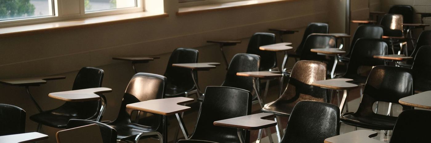 Empty classroom with desks and chairs by windows